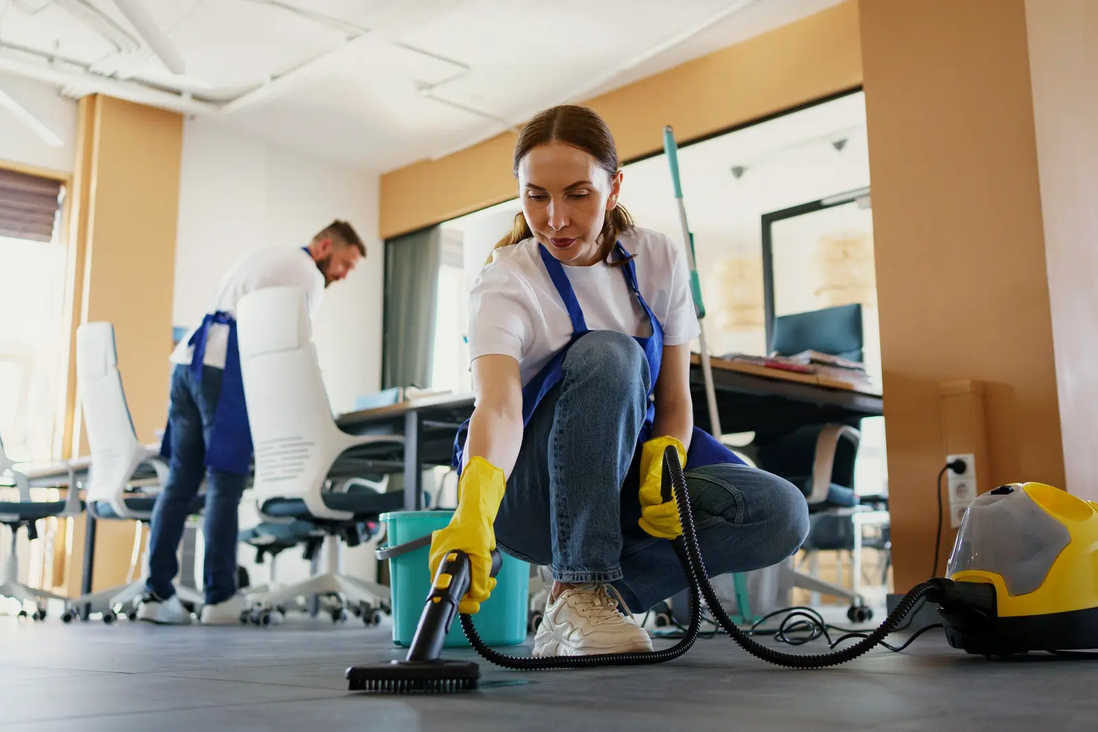 window-cleaning-professionals-heber-utah Cleaning professional spraying and wiping glass window with yellow cloth and rubber gloves