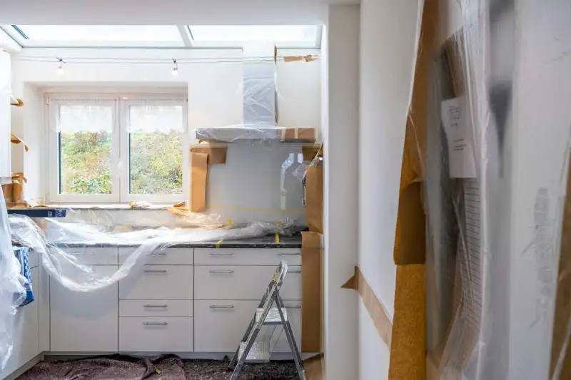Kitchen covered in plastic sheeting and construction debris during home remodel requiring post-construction cleaning in Utah