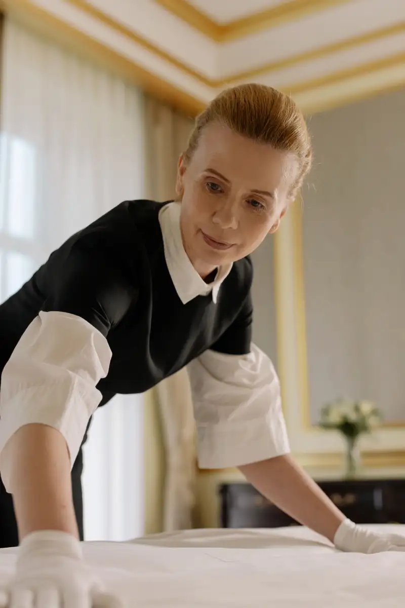 Professional housekeeper making bed during luxury vacation rental turnover cleaning in Utah