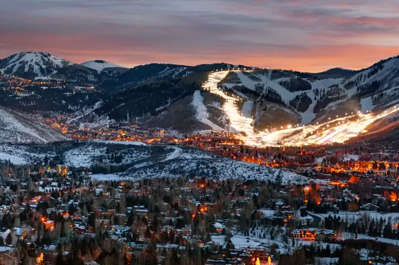 Park City, Utah ski slopes lit up at dusk above homes served by our home cleaning team